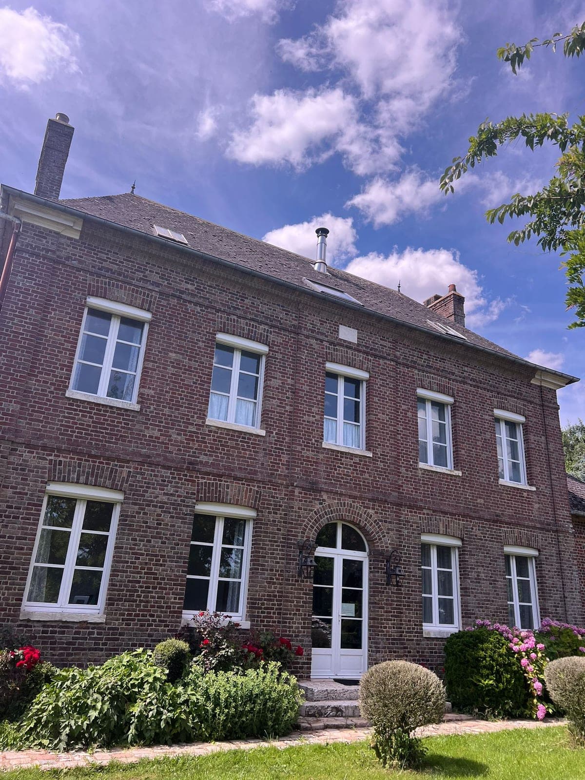Longère en briques rouges surmontée d’une toiture en ardoise.